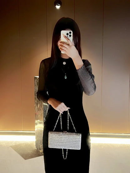 Mujer con vestido negro llevando el bolso plateado de mano